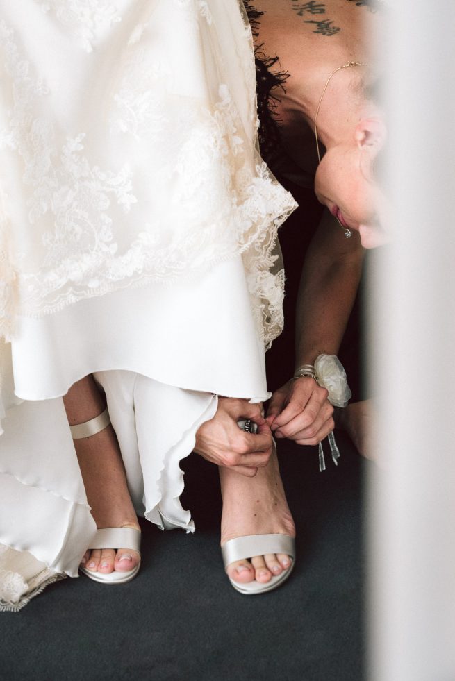 Trauzeugin hilft Braut in ihre Brautschuhe während Getting Ready in Mering